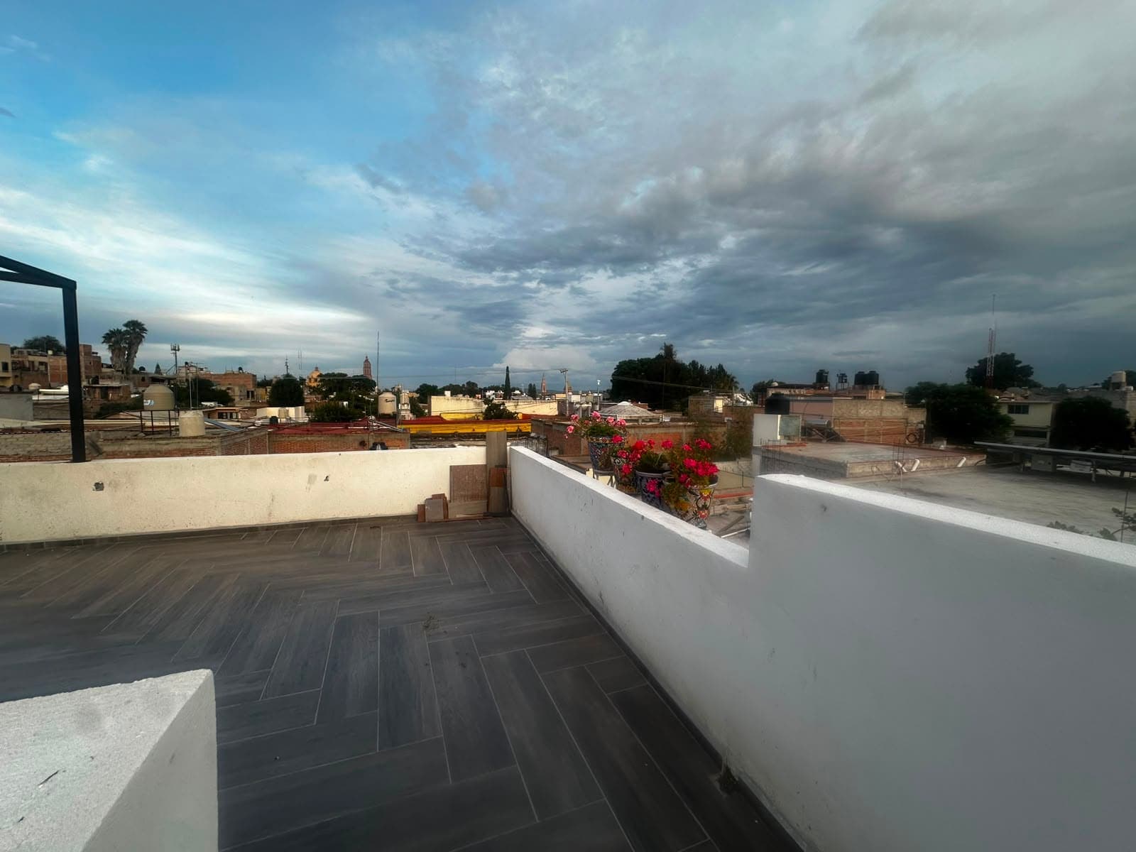 Atardecer desde la terraza, con macetas de talavera y buganvilia sobre el pretil